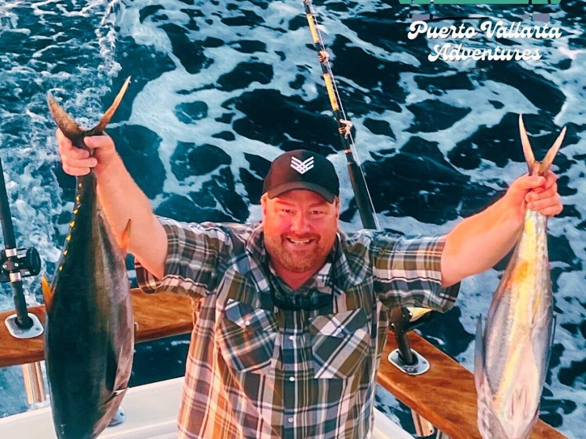 Angler on the back deck of a sportfishing boat holding up two tuna caught off Puerto Vallarta