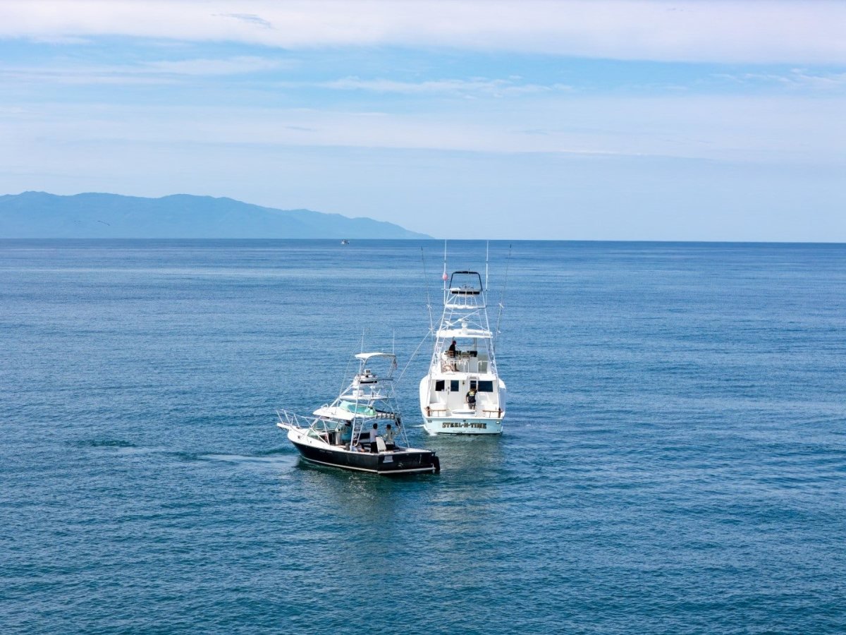 Two private charter boats on the open water of Banderas Bay near Nuevo Vallarta, with mountains on the horizon