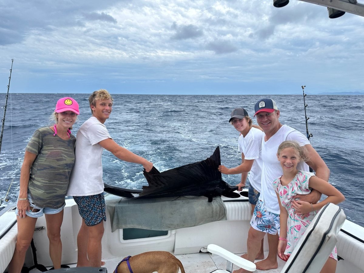A family of five posing on the back deck of a private fishing charter in Banderas Bay with their catch