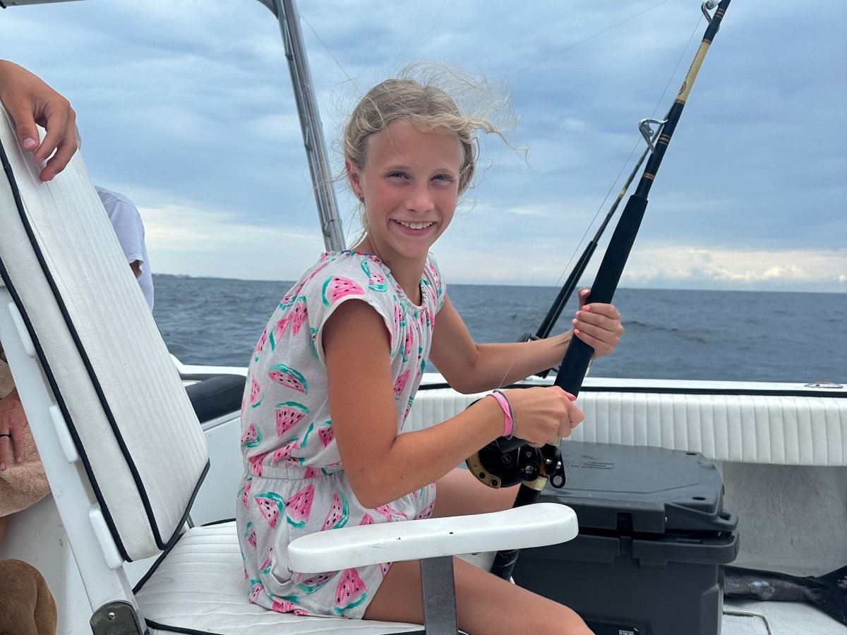 Young girl smiling while holding a fishing rod in the fighting chair of a charter boat in Puerto Vallarta